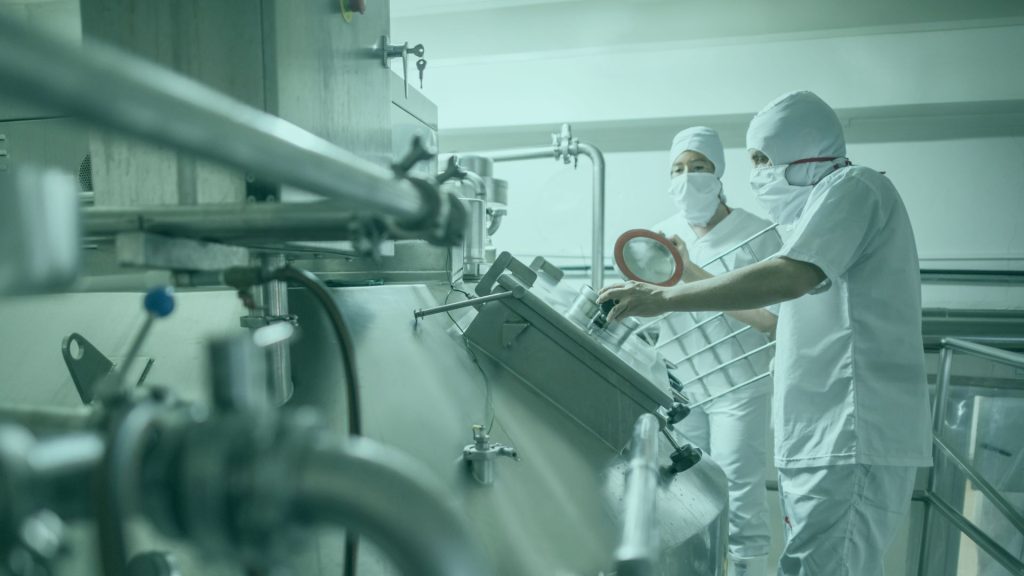 Two people in protective equipment using machine