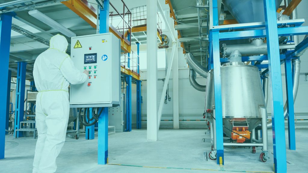 Man wearing PPE using machine in factory